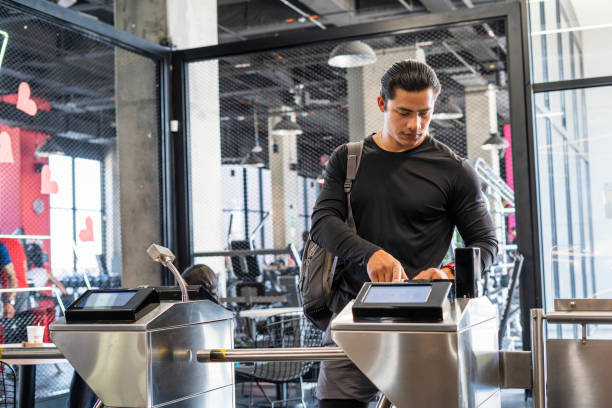 Young man between 25-30 years old entering the gym and registering with his fingerprint to start his exercise routine
