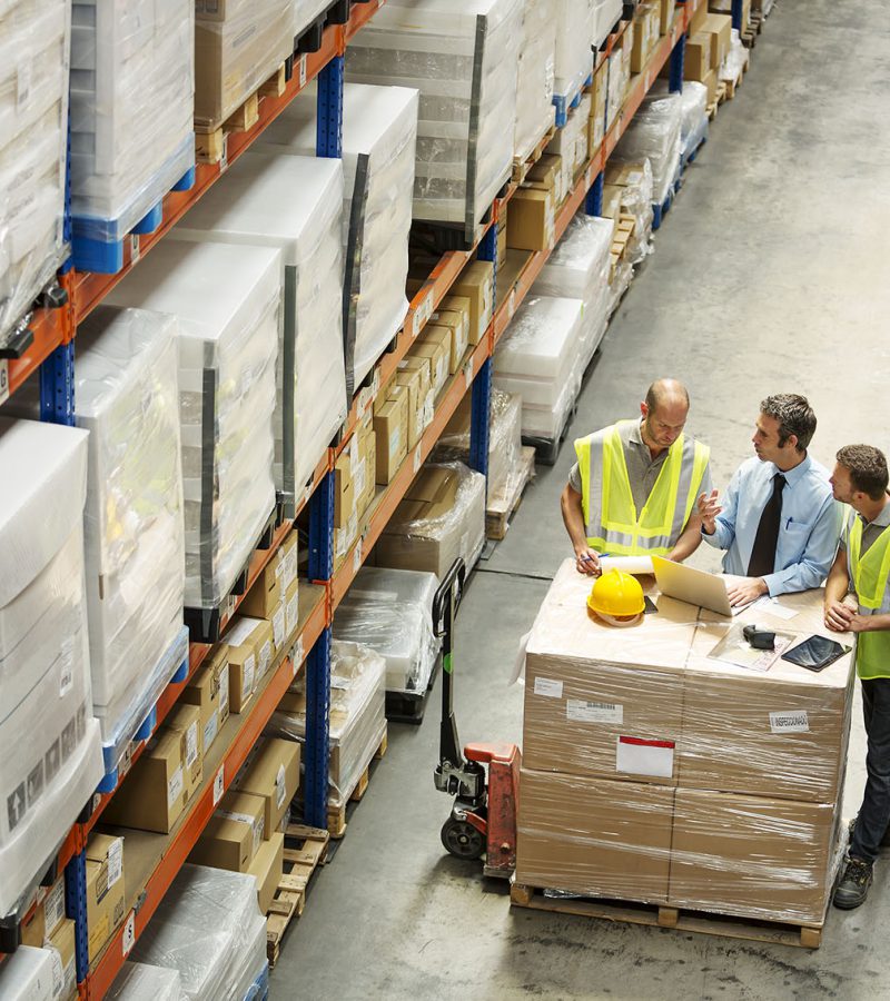 High angle view of supervisor discussing with workers at distribution warehouse