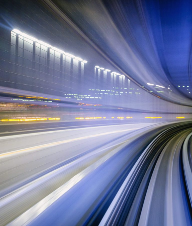 A motion-blurred view from the front of a train as it makes a corner at night in Tokyo, Japan.